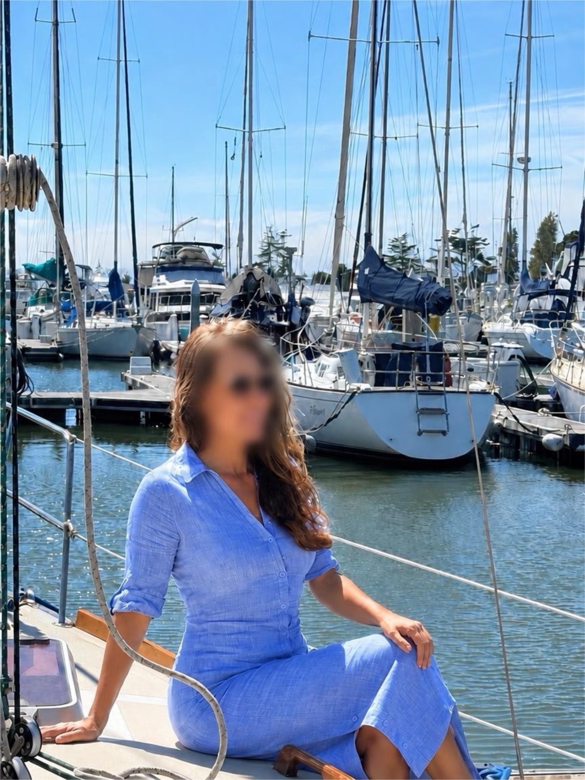 Lina assise sur un voilier dans le port, visage flouté