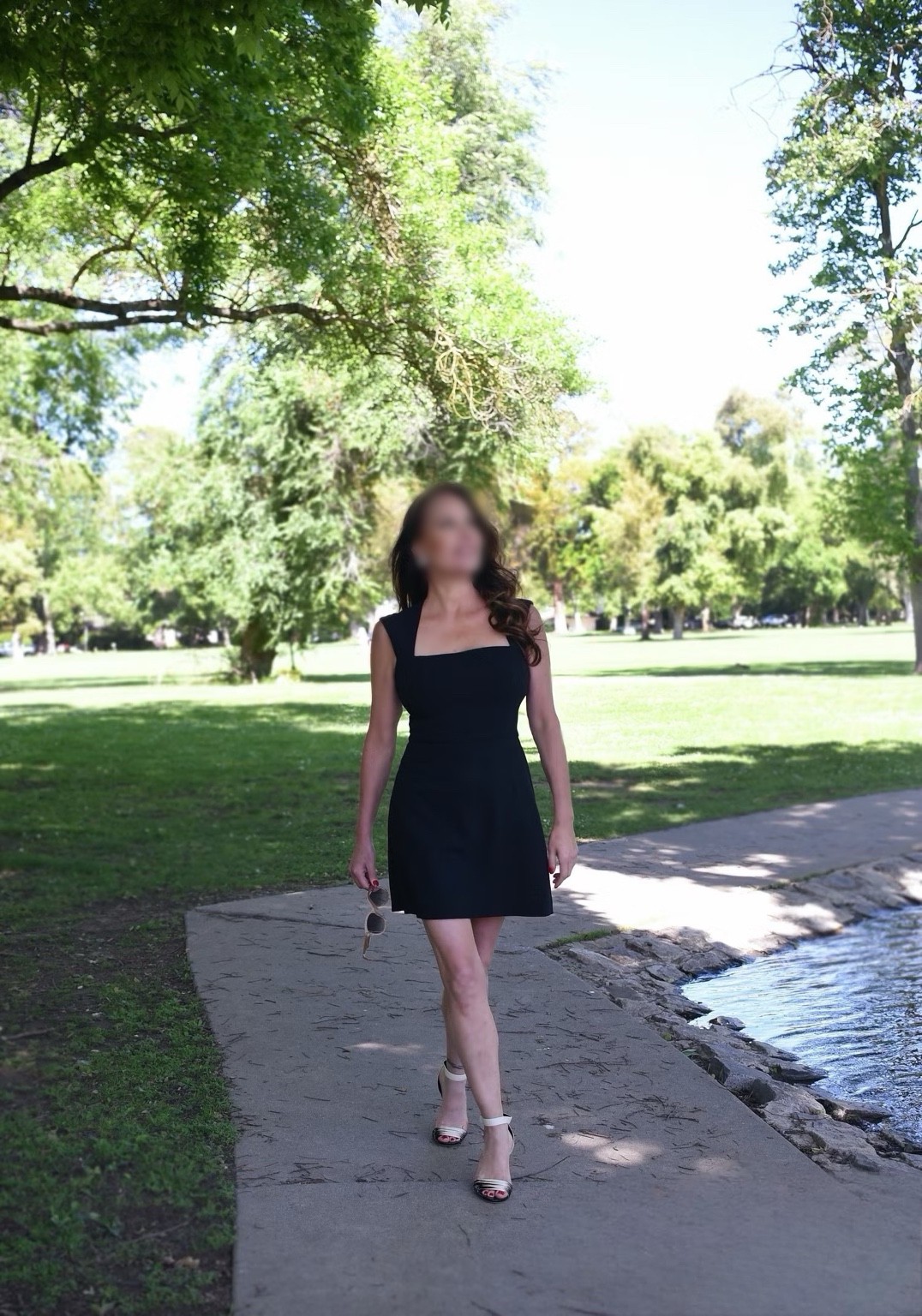 Lina en robe noire dans un jardin, visage flouté